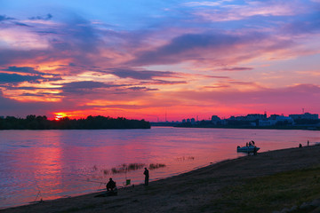 Naklejka na ściany i meble Beautiful bright sunset over the river Irtysh in the city of Omsk, Siberia, Russia. Cityscape at sunset.