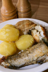 Fried fish and boiled potatoes on a plate.