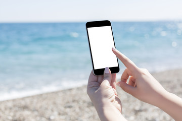 Hand holding a smartphone on a beach