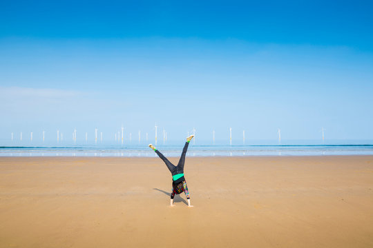 Mature woman doing cartwheel on Redcar beach, North Yorkshire, UK