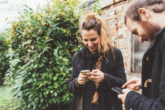 Couple in garden looking at smartphones