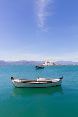 Fototapeta na wymiar Fishing Boats and Bourtzi Fortress in Nafplion, Greece- portrait photo