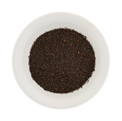 Black loose leaf tea in a small bowl isolated on a white background.