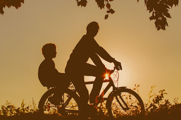 Obraz premium father with son riding bikes at sunset