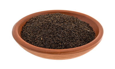 Black loose leaf tea in a small bowl isolated on a white background.