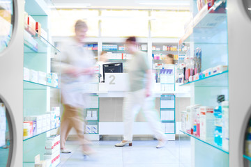 Image défocalisée de clients faisant leurs courses en pharmacie.