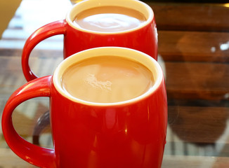 Two cups of coffee milk on glass table.