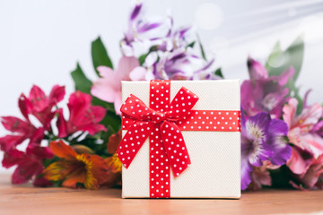 Gift box with spring flowers on wooden table, white background
