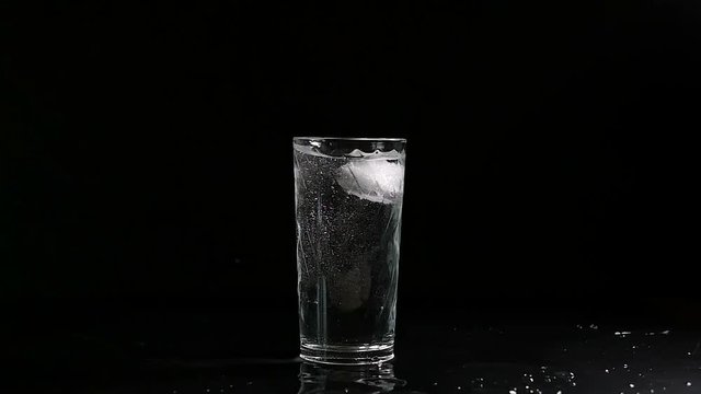 ice cube falling into a glass of water