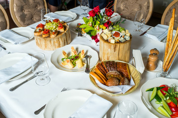 Plates with cold appetizers and cheese sliced on a serving table