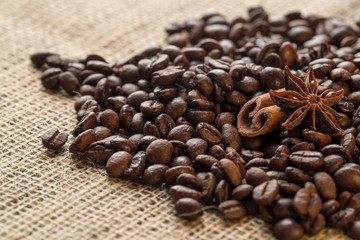 Coffee beans and illicium on a background of burlap. Roasted coffee beans background close up. Coffee beans pile from top with copy space for text. Seasoning. Spice. Badian. Coffee house.