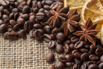 Coffee beans and illicium on a background of burlap. Roasted coffee beans background close up. Coffee beans pile from top with copy space for text. Seasoning. Spice. Badian. Coffee house.