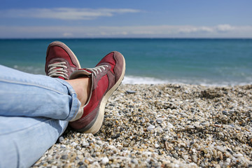 summer vacation selfie- female legs in jeans with fashionable shoes with turquoise in the background