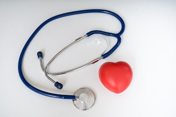 Red plastic heart and stethoscope on white background.