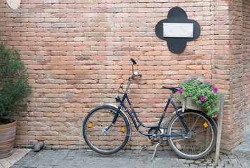 vintage bicycle with basket of flowers leaning against brick wall