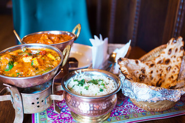 A variety of Indian food with rice in oriental bowls. Rice, soy cheese with vegetables in curry sauce and traditional Indian flat cake