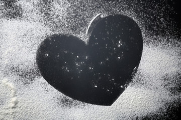 Heart made of flour on dark background, closeup