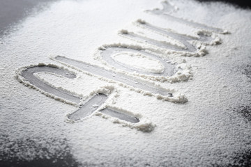Word made of flour on dark table, closeup
