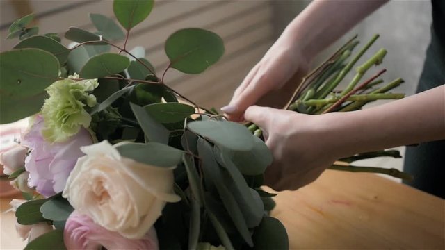 Close up florist making a bouquet of flowers.Peone and roses, focus on the bouquet