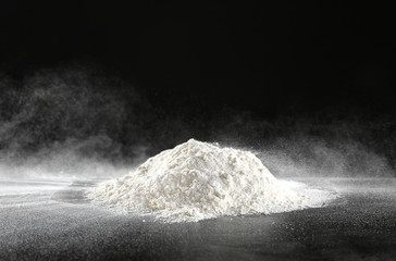 Pile of flour on table against dark background