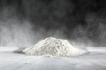 Pile of flour on table against dark background