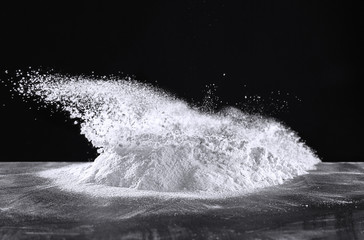Pile of bursting flour on table against dark background