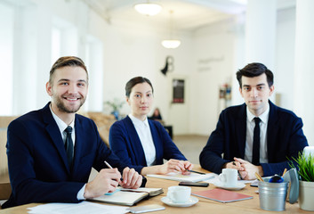 Group of young co-workers sitting by workplace