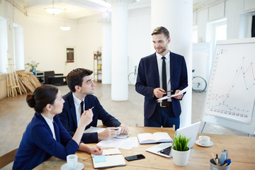 Business group discussing new strategies and listening to report of leader