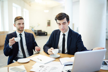 Young men in formalwear looking at data online