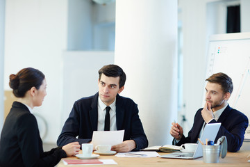 Serious men listening to their colleague idea at meeting