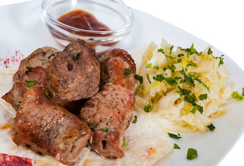 Shashlik. pieces of grilled meat with salad on a plate. isolated on white