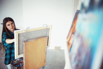 Young artist girl at work in the workshop brush paints canvas inspiration