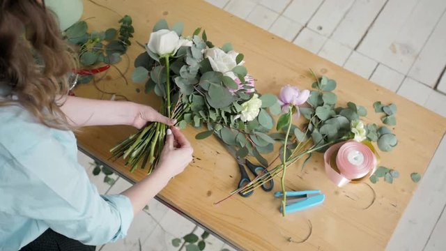 Top View of Female florist making beautiful bouquet at flower shop, peone and rose flower composition for wedding