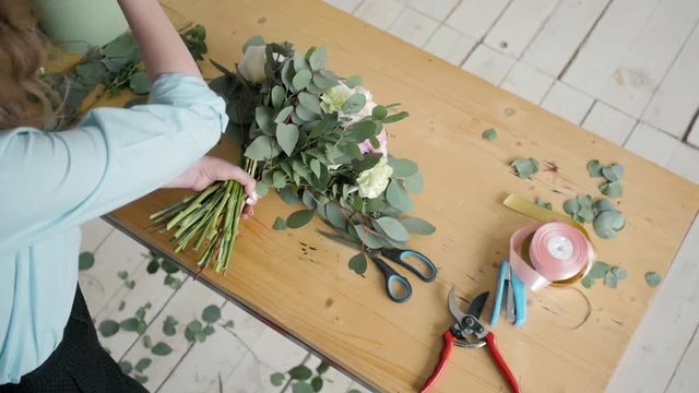 Top View of Female florist making beautiful bouquet at flower shop, peone and rose flower composition for wedding