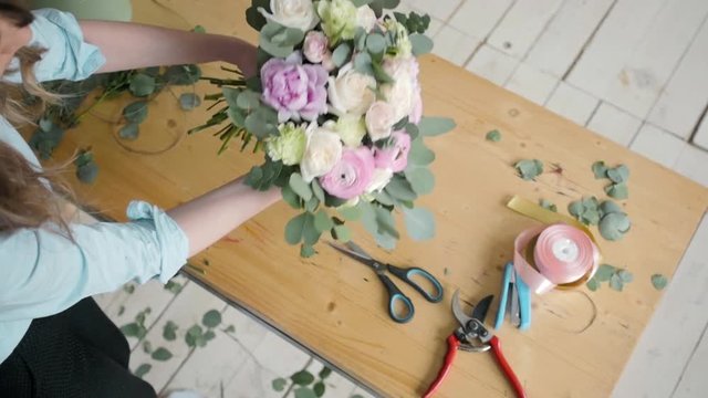 Top View of Female florist making beautiful bouquet at flower shop, peone and rose flower composition for wedding