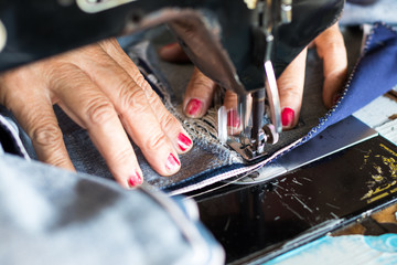 Red nail hand sewing jeans repair.