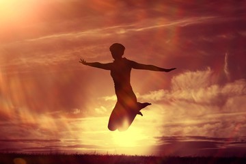 Fototapeta na wymiar Silhouette of a girl against the sky jumping at sunset, concept of happiness