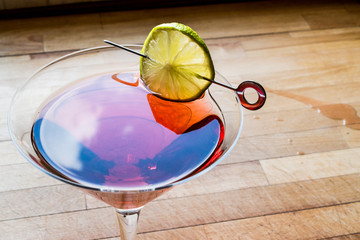 Cosmopolitan Cocktail with lime on wooden surface.