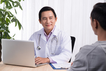 Obraz premium Confident asian male doctor discussing diagnosis with patient in office