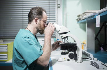 Naklejka na ściany i meble Laboratory research by male scientific using a microscope