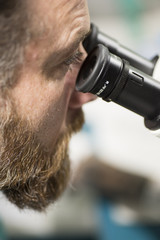 Laboratory research by male scientific using a microscope