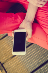 Hands holding mobile phone, wooden floor background. Feeling relax, closeup image