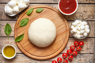 Pizza cooking ingredients: dough, mozzarella, tomatoes, basil, olive oil, cheese, sauce, spices. Work with the dough. Top view Flat lay. Italian food cuisine background pizza margherita preparation