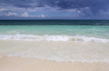 Storm is rising. Turquoise water with big waves. Dramatic sky in the background. 