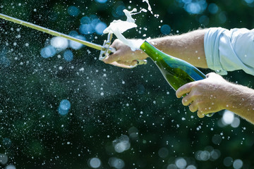 Close up image of a bottle of champagne being opened with a sword, also called sabrage © Dewald