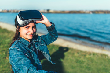 Young girl in virtual reality glasses in the park