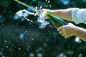 Close up image of a bottle of champagne being opened with a sword, also called sabrage © Dewald