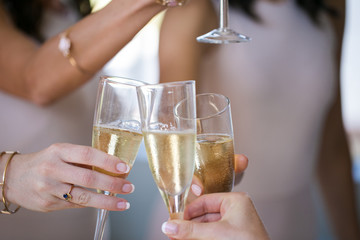 Close up of champagne glasses being chimed together during a toast by a bride and her bridesmaids.