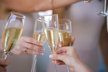 Close up of champagne glasses being chimed together during a toast by a bride and her bridesmaids.