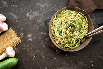 Pasta with zucchini and pesto on dark background. Spaghetti from organic wholegrain flour
